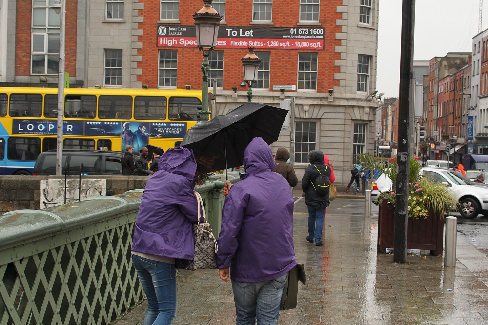 Two people hold their umbrellas tight on a rainy day on Dublin quays.