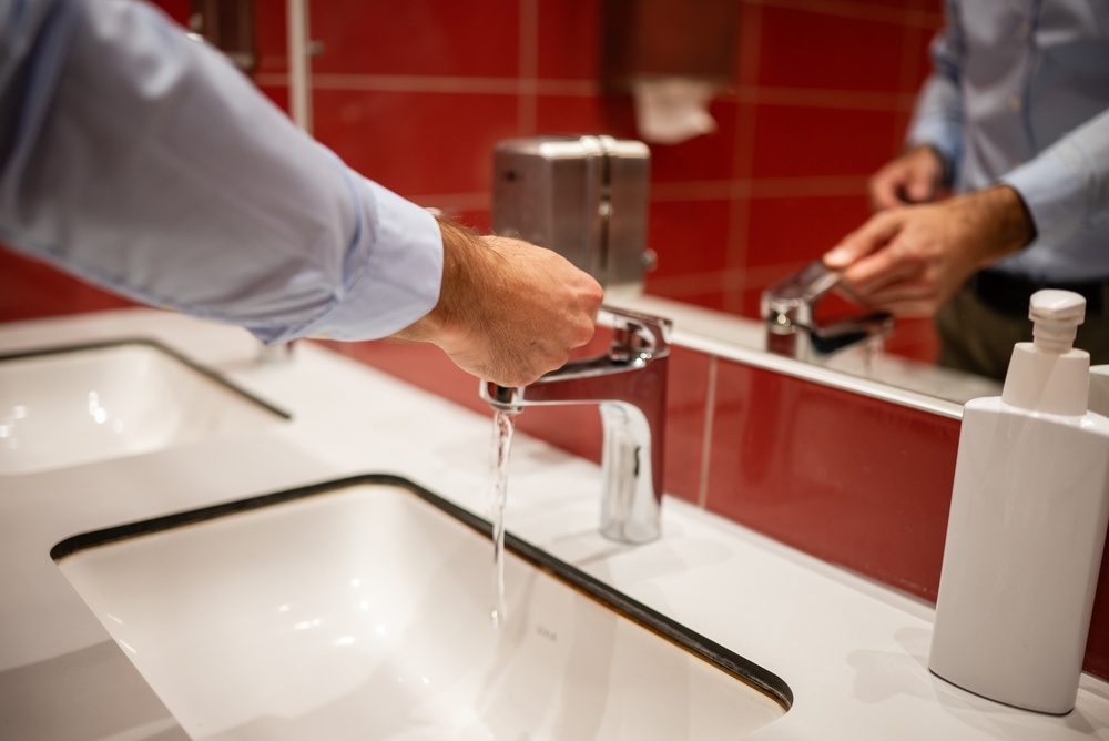 Man washing his hands in public bathroom