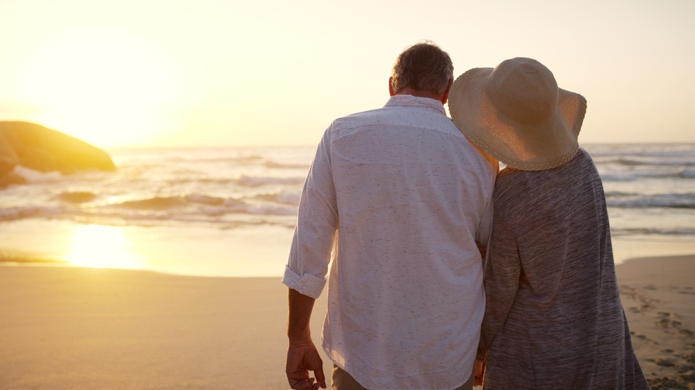 Old couple watching the sunset on a beach