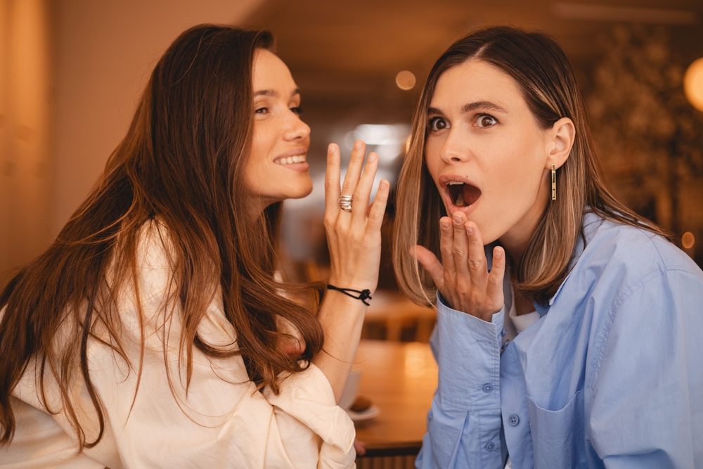Women whispering in ear, gossiping.